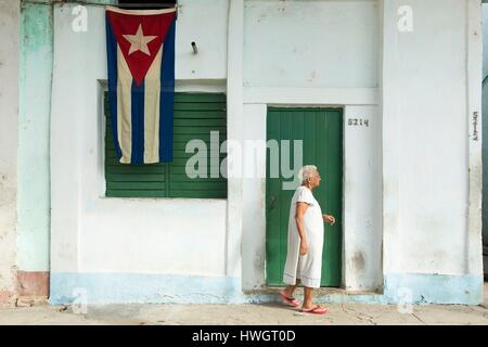 Cuba, Cienfuegos province, Cienfuegos, vecchia donna in piedi dalla porta della sua casa e bandiera cubana Foto Stock