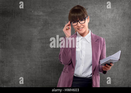 Sorridente insegnante asiatici con libro in piedi di fronte di Blackboard Foto Stock