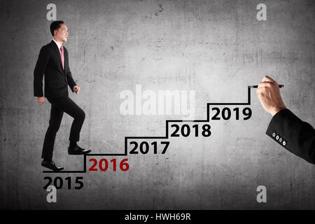 Persona d'affari passo nel disegno a mano con scale 2016 anno su di esso. Business il concetto di destinazione Foto Stock