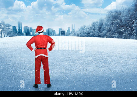 Vista posteriore del giovane uomo che indossa santa claus costume sul campo invernale Foto Stock