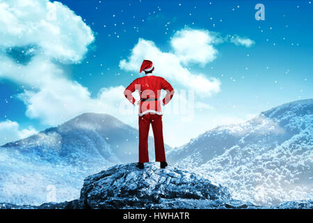 Vista posteriore del giovane uomo che indossa santa claus costume sulla montagna innevata Foto Stock