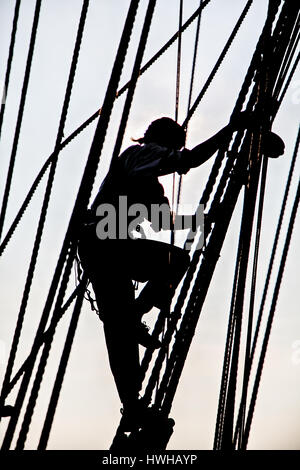 Una silhouette vista di Lady Washington equipaggio arrampicata corda Foto Stock