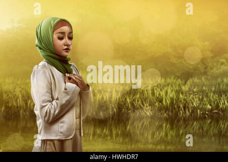 Immagine dei musulmani asiatici donna orante sul campo Foto Stock