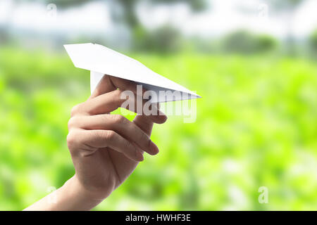 Mano umana tenendo aeroplano di carta pronti per il lancio Foto Stock
