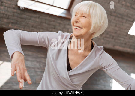 Godendo di felice momento. Allegro età attiva donna di eseguire nella sala da ballo mentre esprimono la positività e l apprendimento di nuove passo di danza Foto Stock