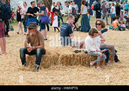 Le famiglie a sedersi su balle di fieno di bere birra e avente un picnic tra la folla al porto Eliot Festival Cornovaglia Foto Stock