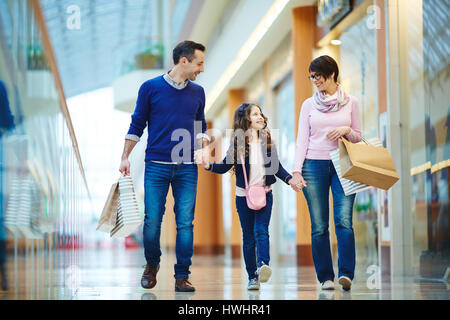 I genitori e la loro figlia percorrendo a piedi il centro commerciale moderno Foto Stock