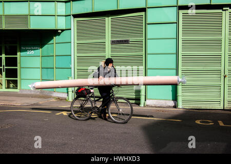 L'uomo spingendo bicicletta con moquette bobina bilanciato sulla parte superiore Foto Stock