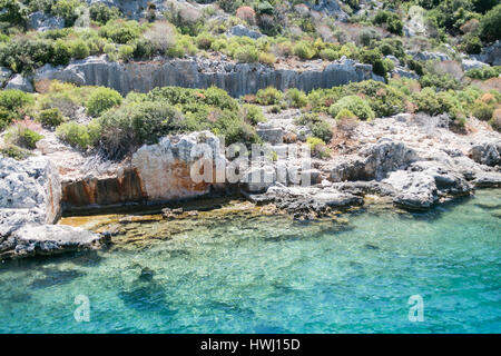 Città Sommersa di Baia vista dal mare in provincia di Antalya in Turchia con turqouise rocce del mare e il verde delle boccole con resti di antiche città visibile sotto wa Foto Stock