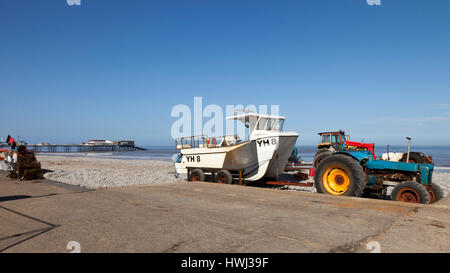 Trattori e barche vicino a Cromer Pier a Cromer Beach in Norfolk England Regno Unito Foto Stock