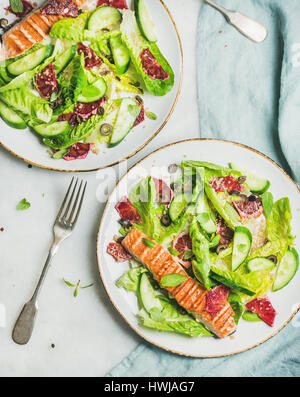 Sana energia migliorando la molla insalata con salmone alla griglia, Arancio sanguigno, olive, cetriolo e quinoa in piastre bianche, vista dall'alto, Sfondo marmo. Clea Foto Stock