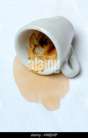 Kaffeefleck auf Tischtuch und umgefallene Tasse, verschuettet Foto Stock