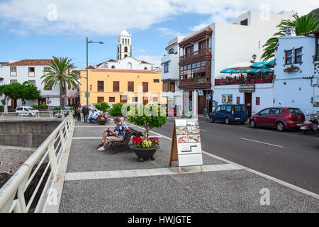 A Garachico, Tenerife, SPAGNA-CIRCA gen, 2016: Senior persone sede vicino a strada TF-42 passando lungo il litorale attraverso le strade della città di Garachico. La Gara Foto Stock