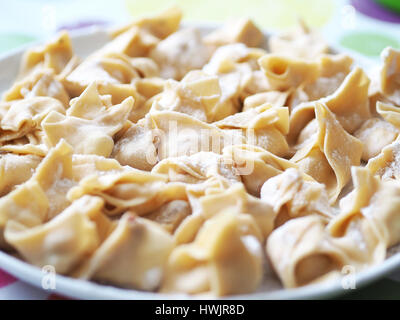 Fatto a mano tortellini con ricotta e pancetta riempimento, fatti con pasta fresca e spolverata di farina Foto Stock