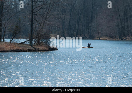 Un singolo KYAKER palette attraverso un tranquillo lago D'inverno. Foto Stock