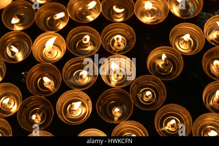 Molte candele accese con la calda fiamma durante la cerimonia religiosa Foto Stock