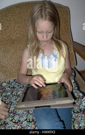Ragazza giovane la riproduzione di un video gioco sul suo ipad o tablet. Ragazza polacca di età di 8 a lavorare il suo dispositivo elettronico. Zawady Polonia centrale Europa Foto Stock