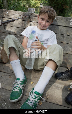 Stanco boy riposo dopo aiutando con faccende familiari acqua potabile età 10. Zawady Polonia centrale Europa Foto Stock