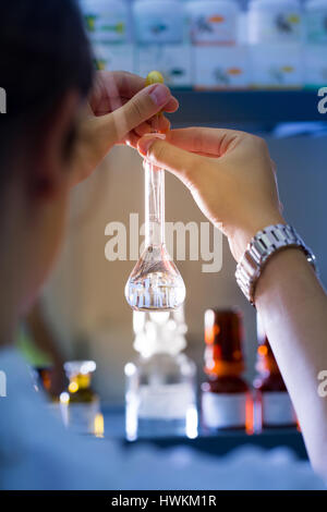 Donna professionale, tecnico di laboratorio che lavora in un laboratorio medico con pallone a fondo tondo. Medicina, sanità, attrezzature di laboratorio, scienza concep Foto Stock