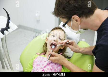 Bambino paziente seduto sulla poltrona odontoiatrica in età pediatrica dentisti office sul suo regolare di Checkup per la carie e malattie gengivali. La prevenzione precoce, igiene orale Foto Stock