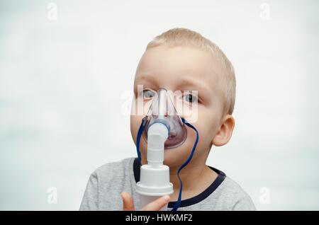 Bambino rendendo inalazione con maschera sul suo volto. Problemi di asma concept Foto Stock