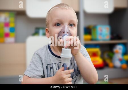 Bambino rendendo inalazione con maschera sul suo volto. Problemi di asma concept Foto Stock