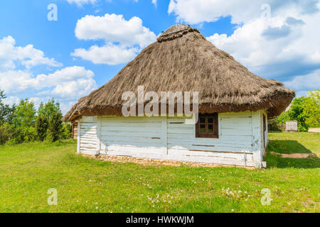 Vecchia casa tradizionale con tetto di paglia nel villaggio Tokarnia sulla soleggiata giornata di primavera, Polonia Foto Stock