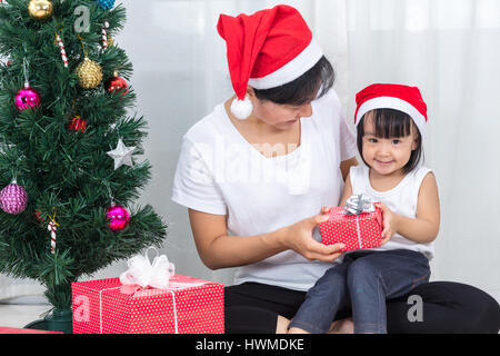 Asian madre cinese e la figlia seduta accanto ad albero di Natale a celebrare il Natale e il nuovo anno. Foto Stock