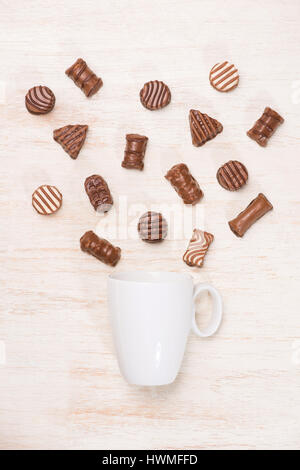 Un bicchiere di latte al cioccolato e la varietà di cioccolatini sul tavolo Foto Stock