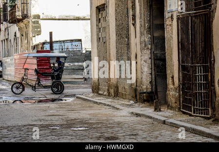 L'Avana, Cuba - Gennaio 5, 2016: tipica scena di una delle strade del centro di La Havana - architettura coloniale, Rickshaw taxi bicicletta Foto Stock