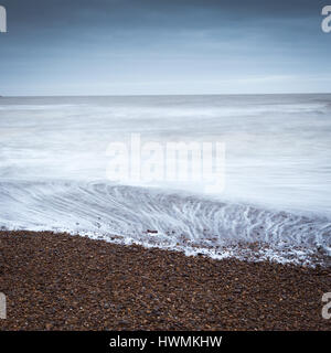 Mattina minimalista sunrise seascape con spiaggia di ciottoli e cielo blu a Shingle Street Suffolk Foto Stock