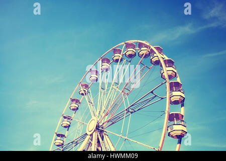 Vintage immagine stilizzata di una ruota panoramica Ferris contro il cielo blu. Foto Stock