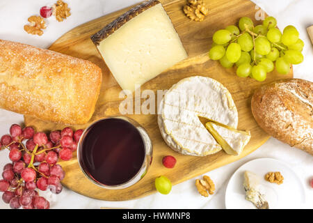 Una foto aerea di un bicchiere di vino rosso con formaggio bianco e il pane di segale, viola e verde UVA e noci, in corrispondenza di un abbinamento vino Foto Stock