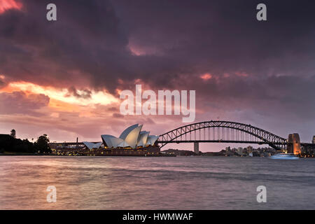 Sydney, Australia - 19 Marzo 2017: Sydney Opera House e Harbour Bridge durante le tempeste e arancione tramonto intorno al Porto di Sydney. Foto Stock