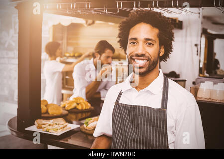 Flare contro bello cameriere sorridente in telecamera Foto Stock