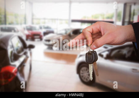 Donna felice ricevere le chiavi dell'auto contro le automobili parcheggiate presso showroom Foto Stock