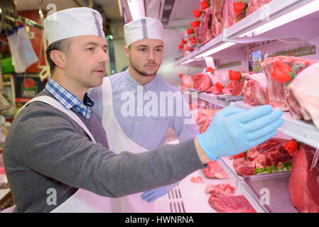 Macellaio di insegnamento di una giovane come vendere la carne Foto Stock