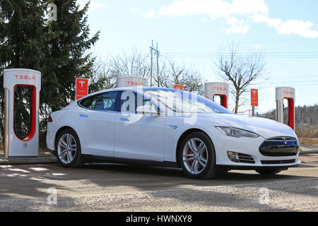 PAIMIO, Finlandia - 18 Marzo 2017: Bianco Tesla Model S P85D auto elettrica è in carica di Tesla sovralimentatore. Il sovralimentatore stazioni aggiungere ca Foto Stock