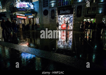 Vista notturna di persone e di riflessioni su strada bagnata in piccadilly circus Foto Stock