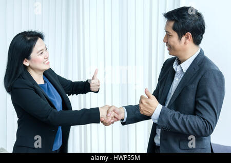 Il successo del team aziendale concetto. Donna asiatica e di uomo e di handshake che mostra Thumbs up. Foto Stock