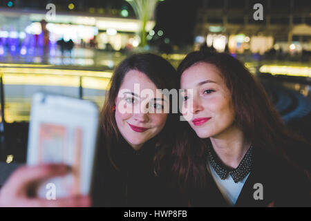 Due giovani belle donne caucasici amici prendendo selfie con smart phone tenere in mano - vanity, condivisione sociale il concetto di rete Foto Stock