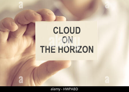 Primo piano su imprenditore tenendo una scheda con il testo il cloud all'orizzonte, business Concetto di immagine con soft focus background e tono vintage Foto Stock