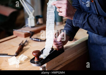 Sezione mediana del falegname pianificazione tavolato in legno in laboratorio Foto Stock