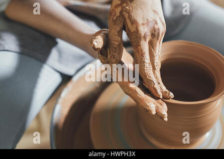 Angolo di alta vista di potter argilla di sagomatura sulla ruota di filatura in officina Foto Stock