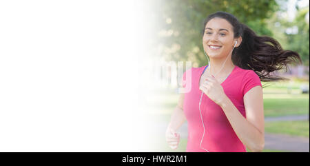 Sportivo da donna graziosa jogging in un parco mentre si ascolta la musica Foto Stock