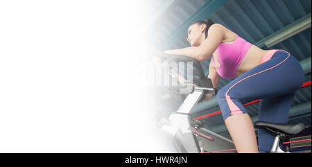 Basso angolo vista di una determinata giovane donna che lavora fuori alla classe di filatura in palestra Foto Stock