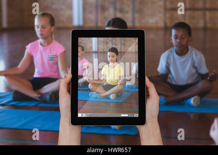 Close-up di mani digitale compressa contro la scuola i bambini durante la meditazione Yoga classe Foto Stock