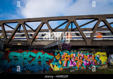 Un treno overground correre veloce durante l'attraversamento di un ponte in prossimità di Bricklane comunità di nomadi dove la parete sono pieni di graffiti artistici Foto Stock