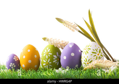 Grappolo di uova di pasqua in colori pastello su erba, isolati su sfondo bianco Foto Stock