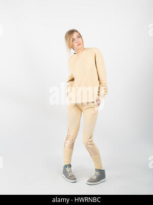 Giovane bella ragazza che indossa abiti di colore giallo e di sneakers in posa isolati su sfondo bianco Foto Stock